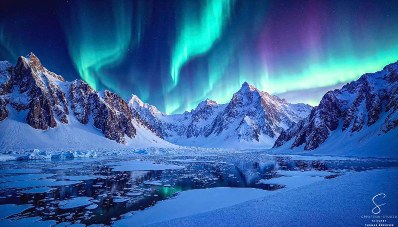 Polarlichter über verschneiten Berggipfeln